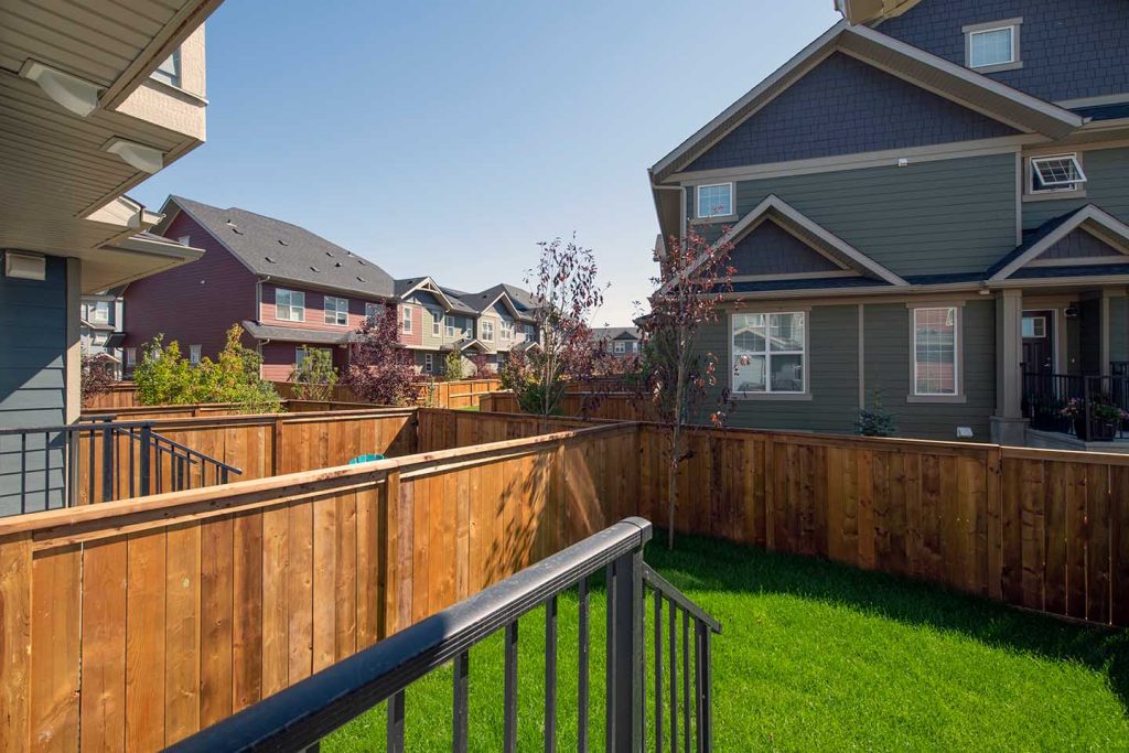 A backyard at ZEN Riverstone West with a wood fence and green grass