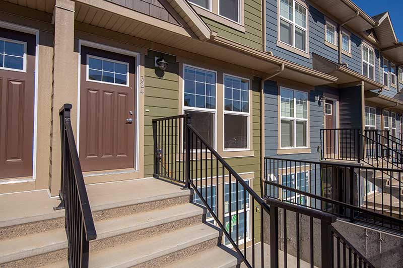 multi-coloured exterior of Zen Riverstone West townhome building with black metal railing and concrete steps