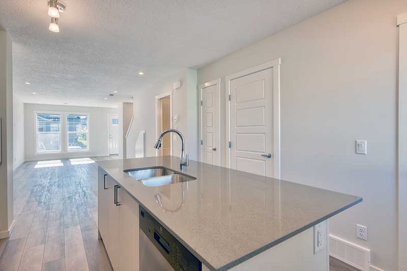 bright open living room space in the background and kitchen island with quartz countertop in the forefront