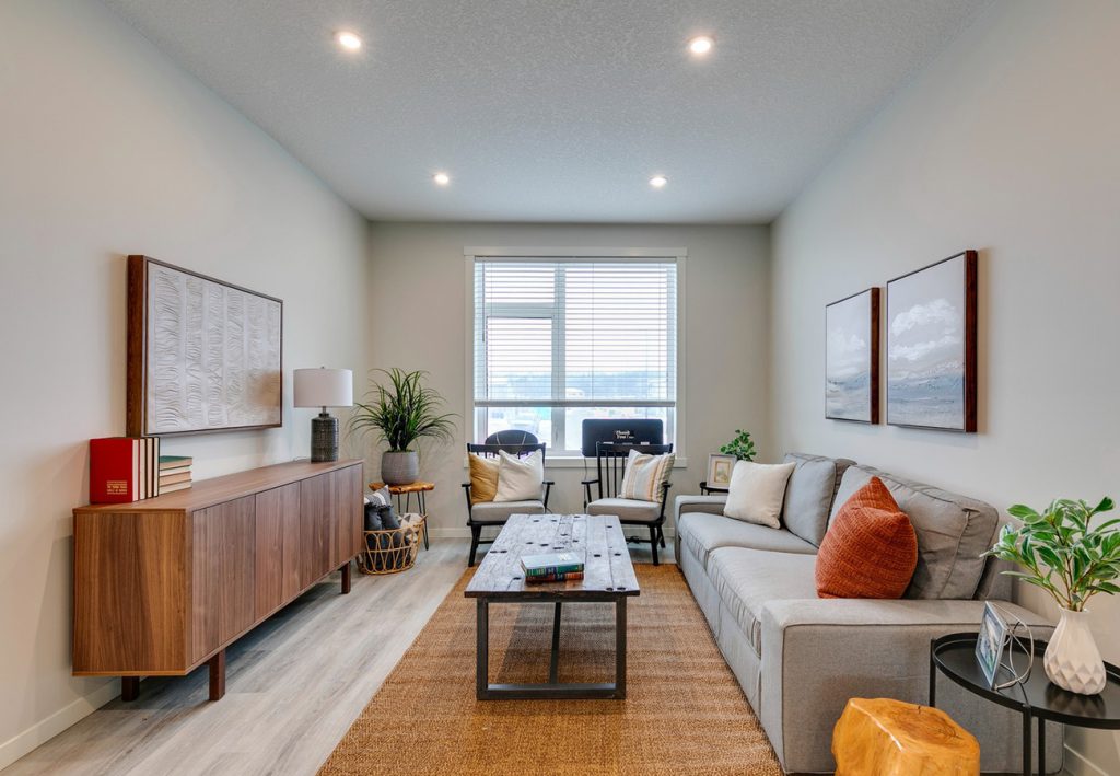 ZEN Greystone showhome living room with large window, modern furniture, neutral tones, and wood-accented decor by Avalon Homes.