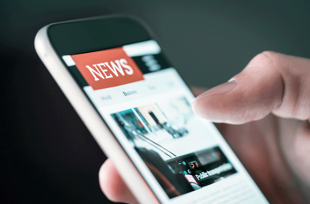 A close-up of a person's hand holding a smartphone and scrolling through a digital news application.