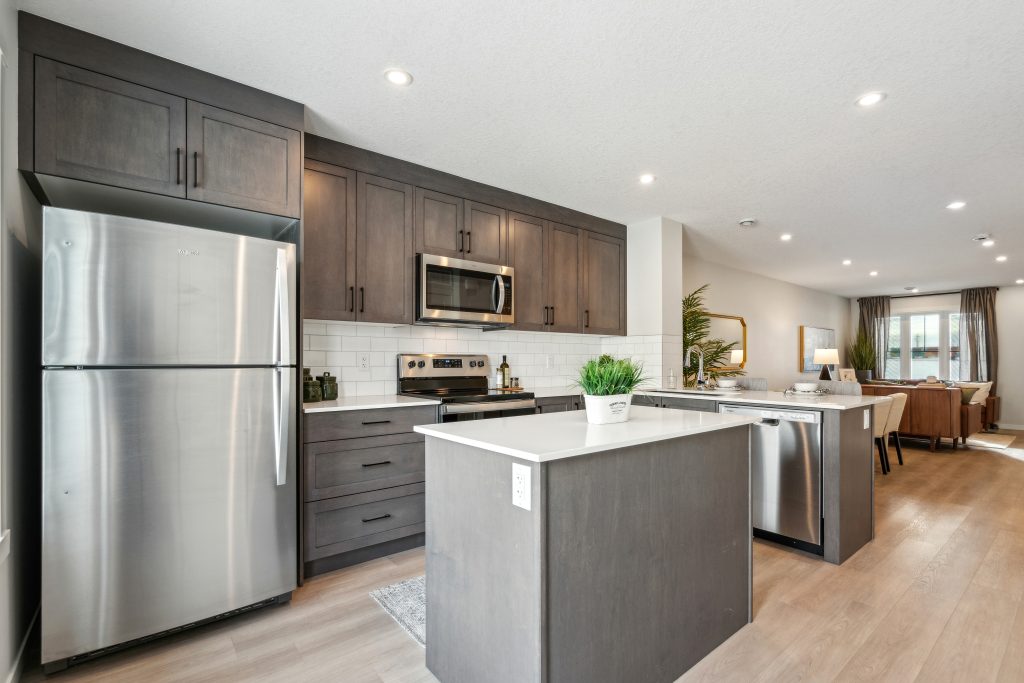 Modern, open-concept kitchen and living area in an Avalon Homes townhome, showcasing a right-sized floorplan with stainless steel appliances and natural light.